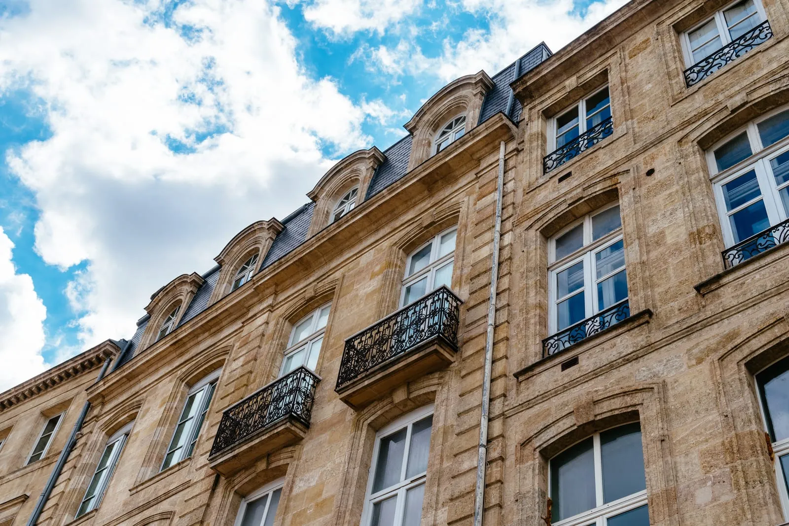Une façade bordelaise en pierre de taille et ses balcons en fer forgé, vue d’en bas