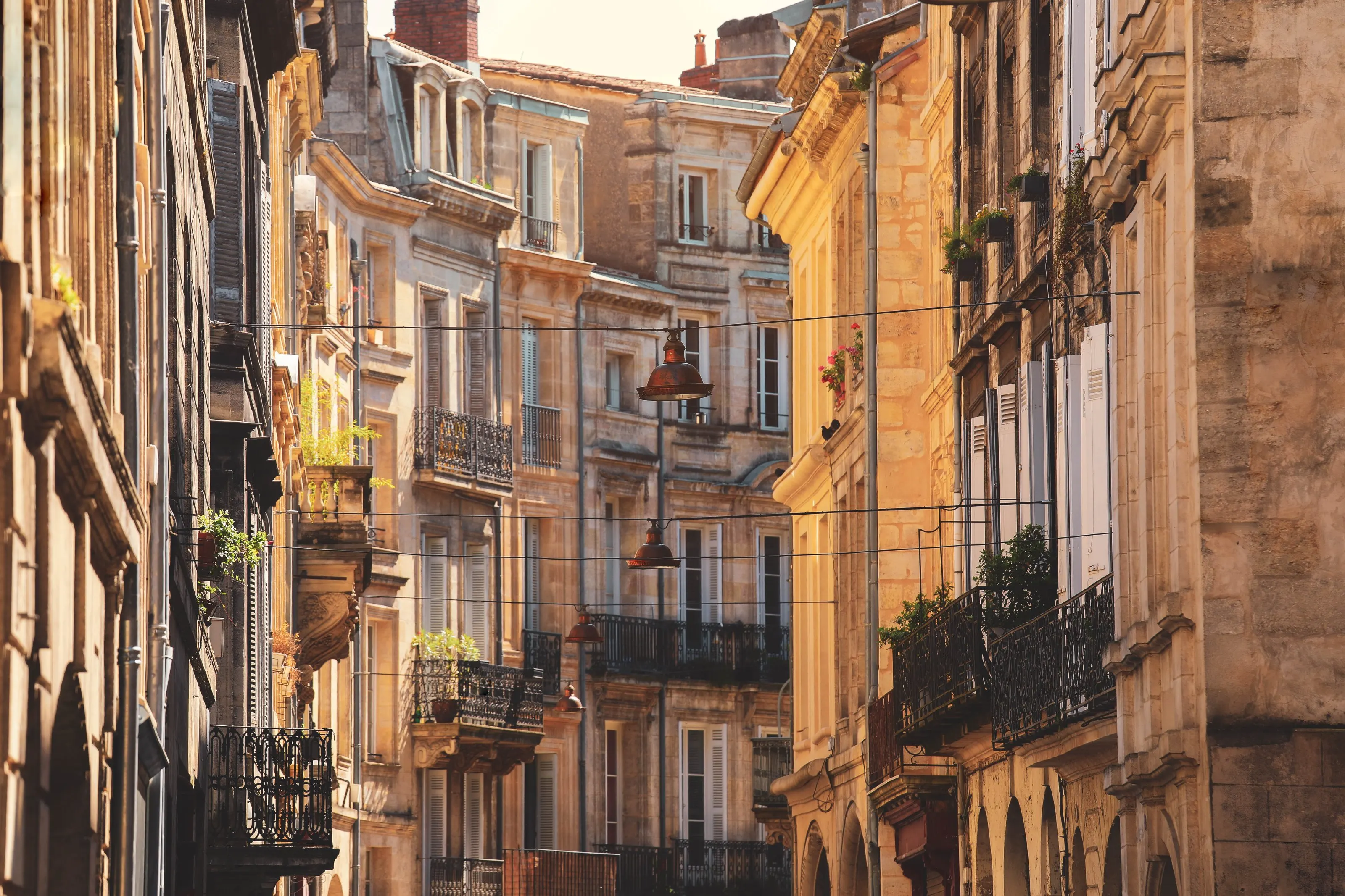 Les façades de pierre blonde et les balcons en fer forgé d’une rue de Bordeaux