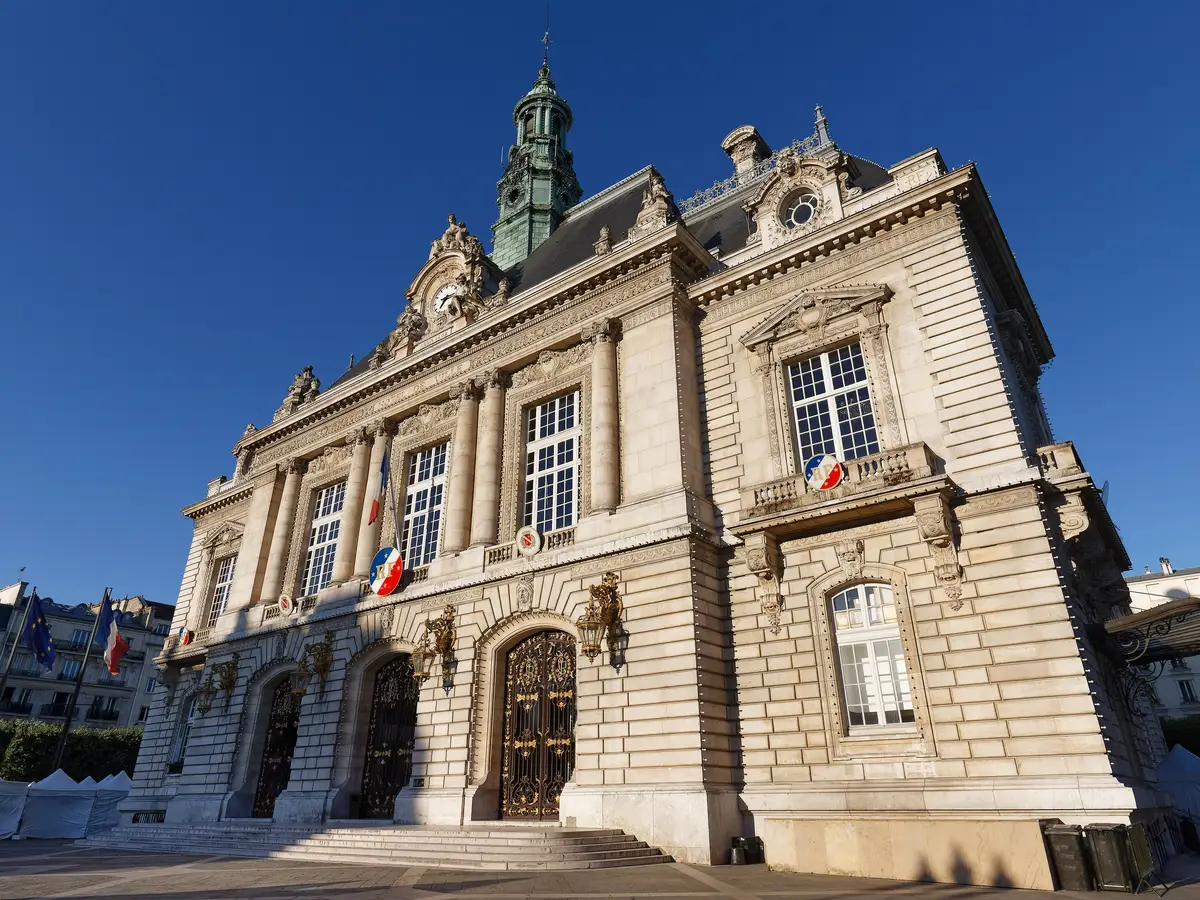 A câmara municipal de Levallois-Perret, a sua fachada de pedra esculpida e o seu campanário sob o céu azul