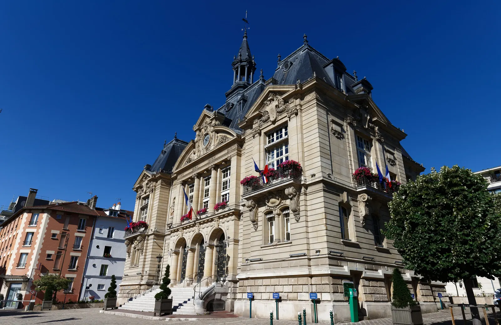 The town hall of Suresnes, its stone façade and bell tower, its flowered balconies under a blue sky