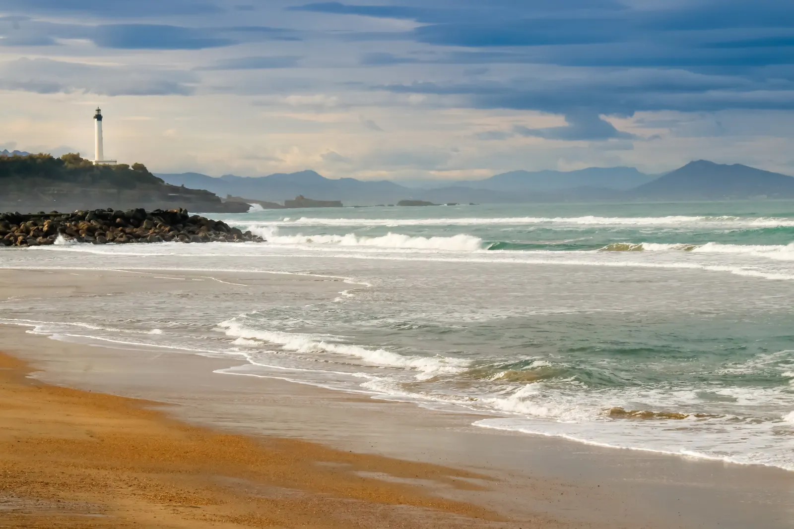 A beach in Anglet at low tide, the Atlantic waves and the Basque coast stretching to the mountains