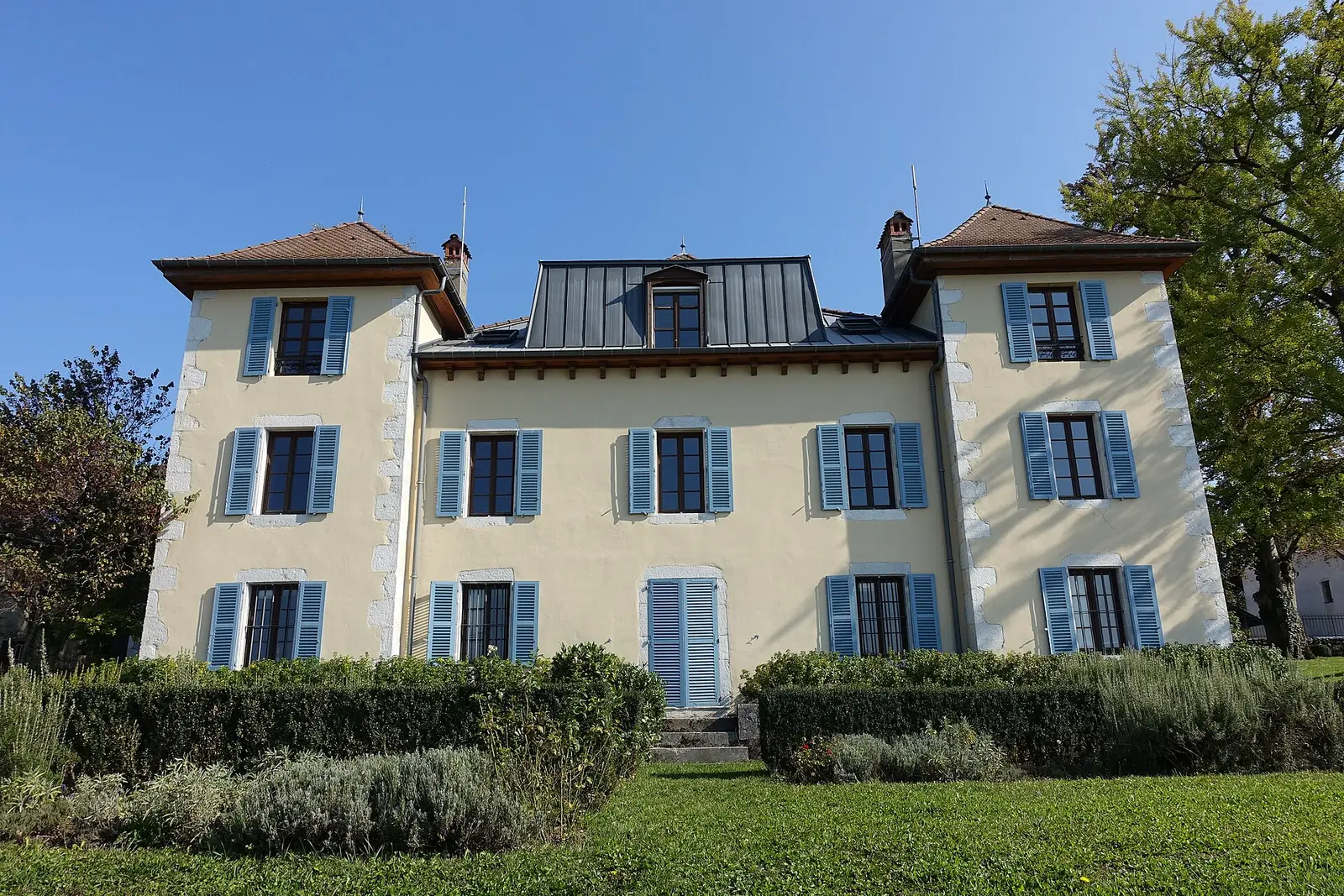 Casa savoyarda em Annecy, fachada creme e persianas azuis