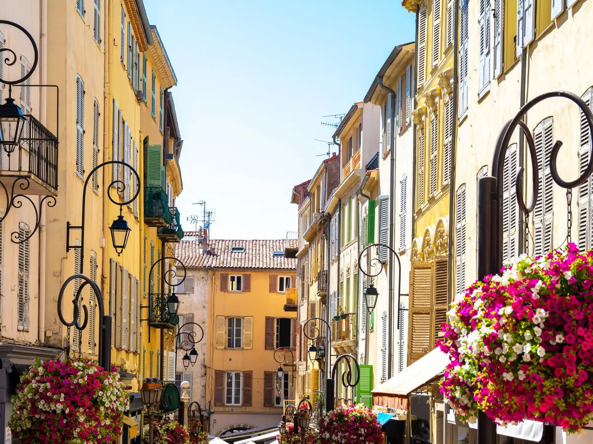 A flower-lined lane in the old town of Antibes, ochre façades and wrought-iron lanterns