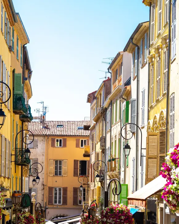 A flower-lined lane in the old town of Antibes, ochre façades and wrought-iron lanterns