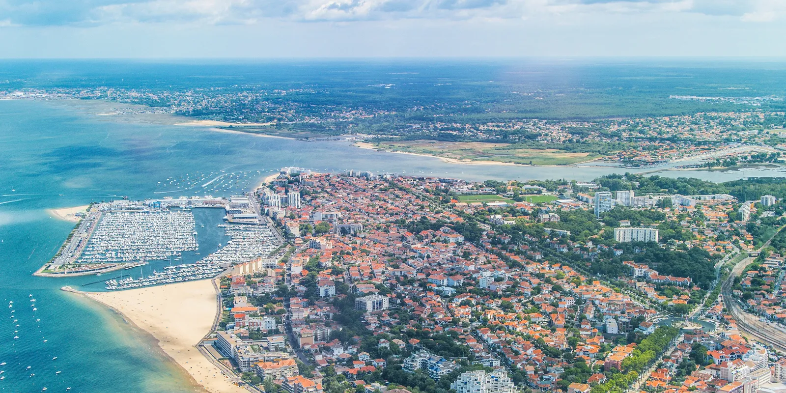 Arcachon vue du ciel : le port de plaisance, la plage et les toits de la ville au bord du bassin