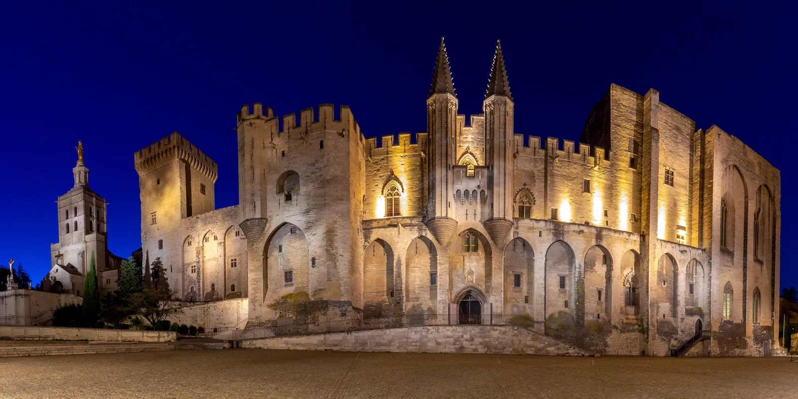 Le palais des Papes d’Avignon illuminé la nuit, et le clocher de la cathédrale Notre-Dame-des-Doms