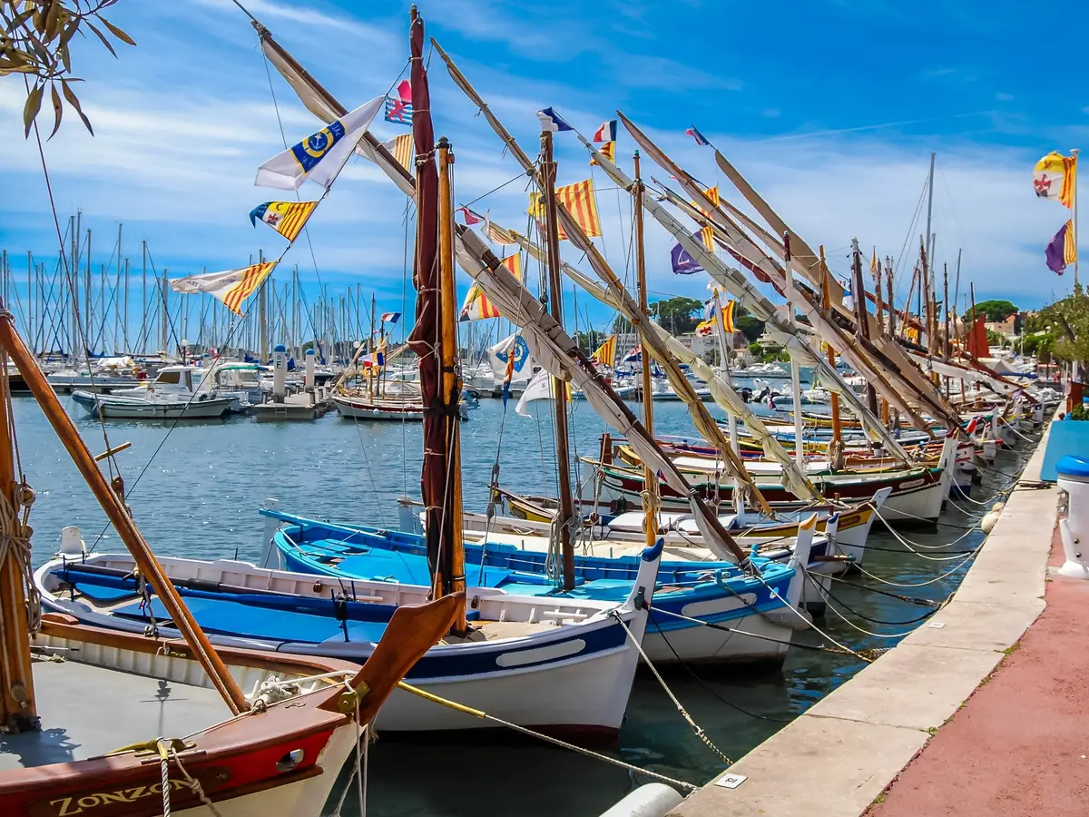 Os barcos tradicionais embandeirados no cais do porto de Bandol, os seus mastros e flâmulas sob o céu azul