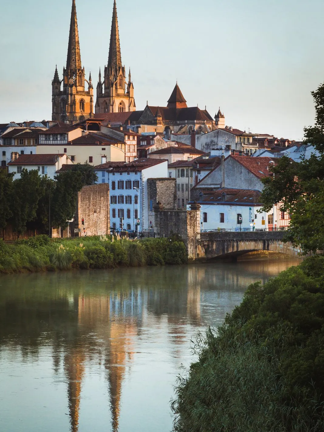 A catedral de Sainte-Marie de Bayonne e as suas duas flechas acima das casas, refletidas no Nive