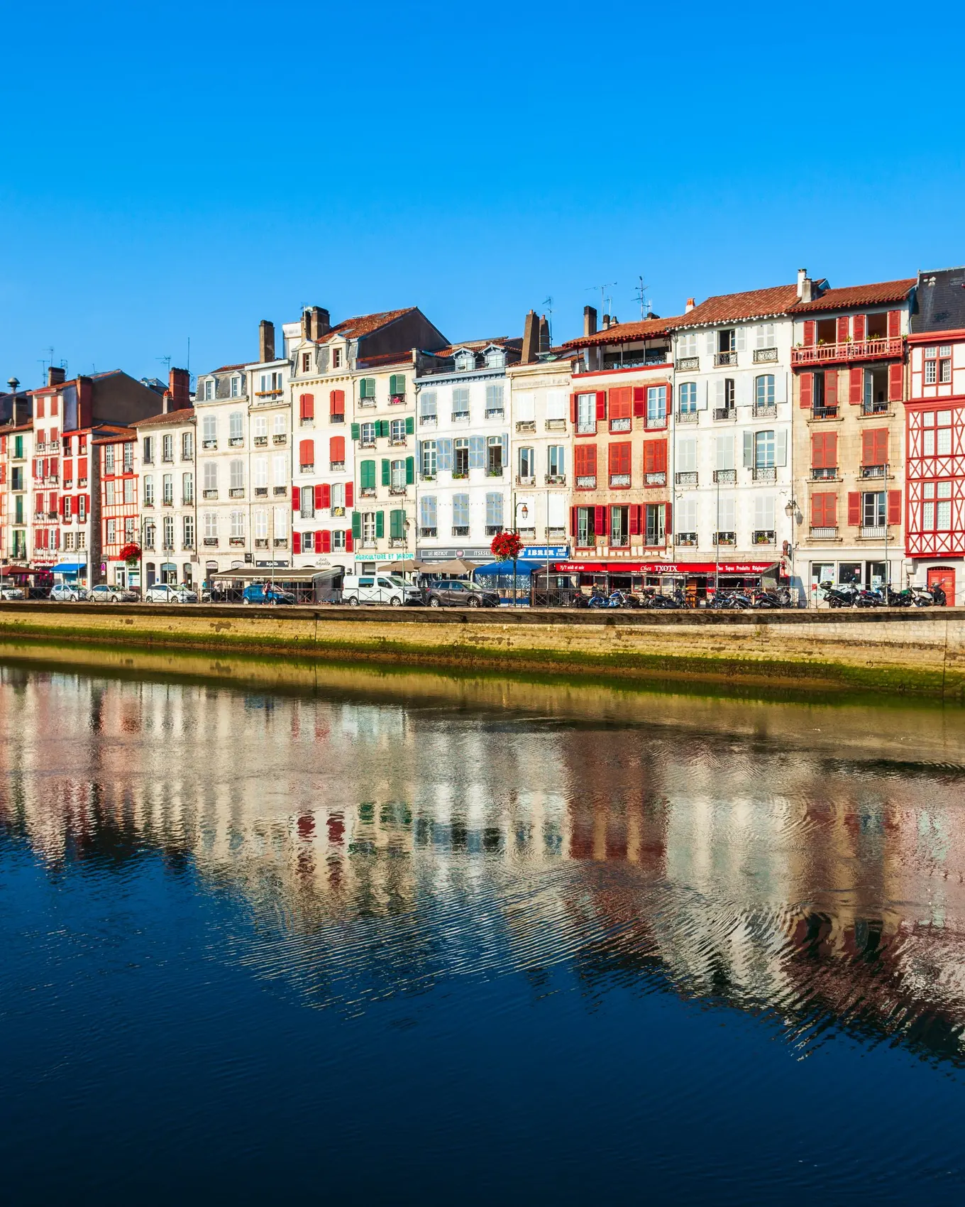 Les façades colorées des quais de Bayonne et leurs reflets dans la rivière