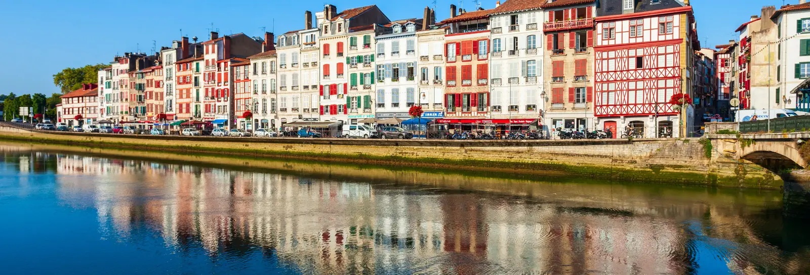 Les façades colorées des quais de Bayonne et leurs reflets dans la rivière