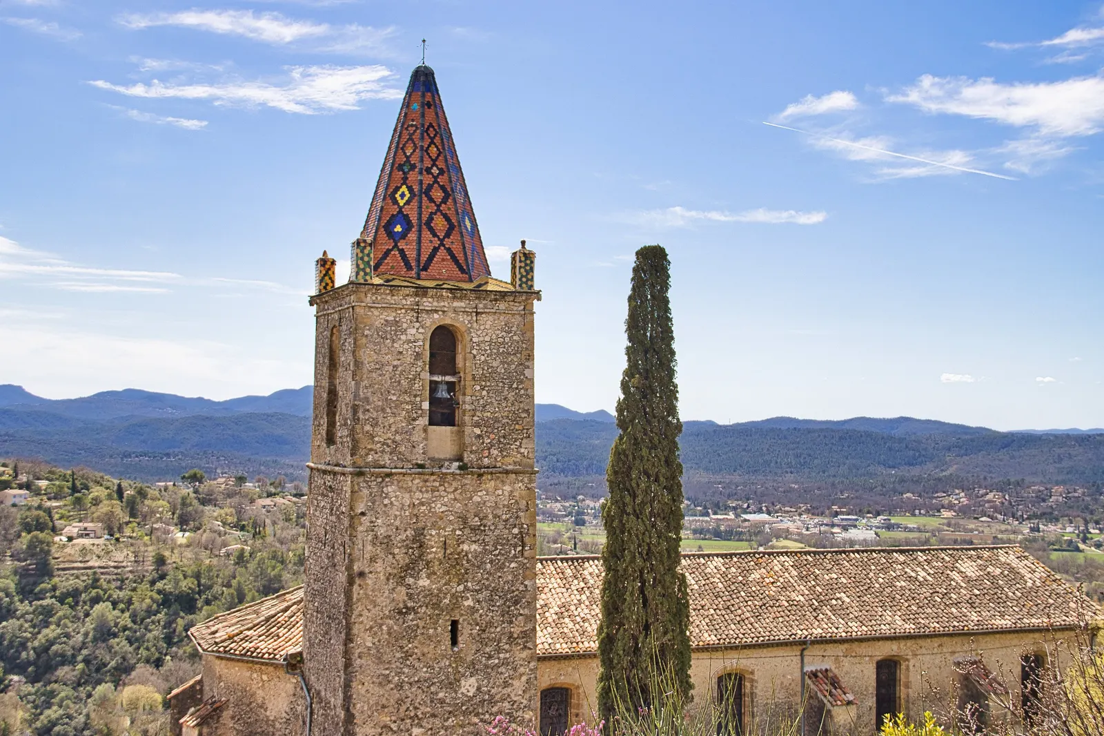 The bell tower of the church of Saint-Donat in Callian, a hilltop village of the Pays de Fayence, and the hills of the Var