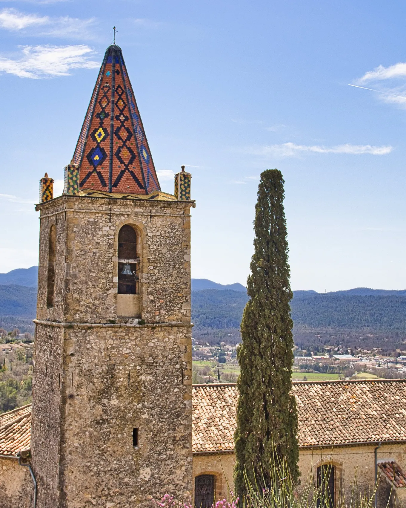 The bell tower of the church of Saint-Donat in Callian, a hilltop village of the Pays de Fayence, and the hills of the Var