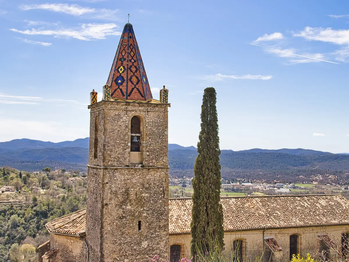The bell tower of the church of Saint-Donat in Callian, a hilltop village of the Pays de Fayence, and the hills of the Var