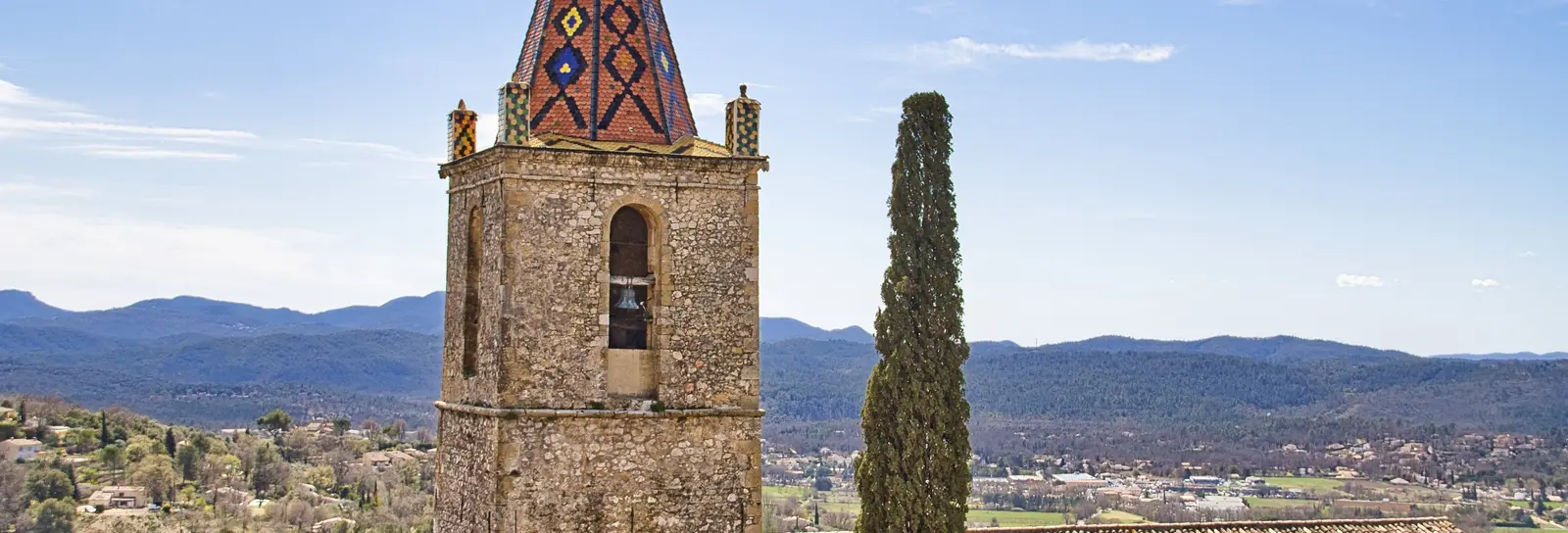 The bell tower of the church of Saint-Donat in Callian, a hilltop village of the Pays de Fayence, and the hills of the Var