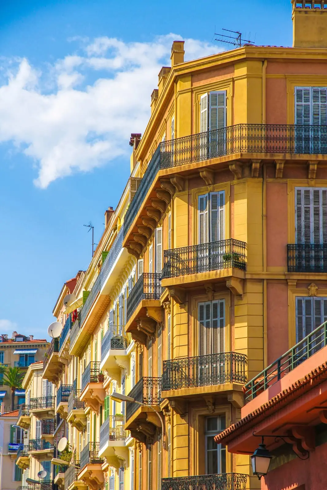 Un immeuble Belle Époque jaune et ses balcons en fer forgé