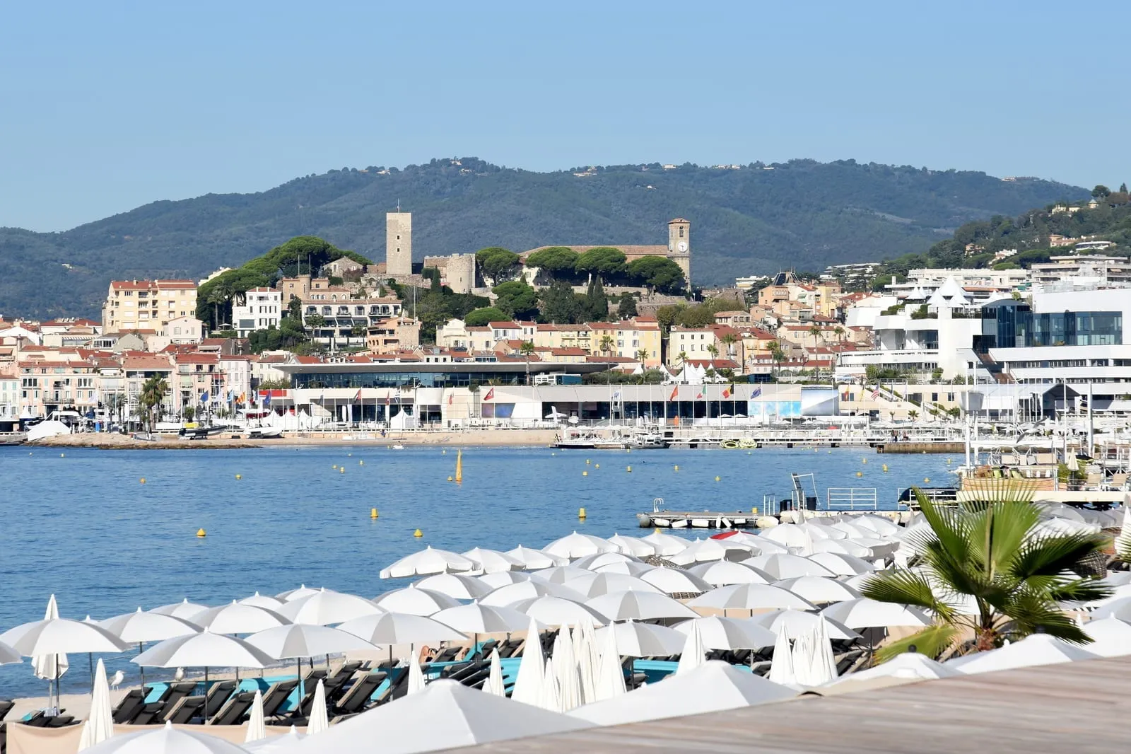 Le Suquet et sa tour au-dessus du port, les parasols d’une plage au premier plan