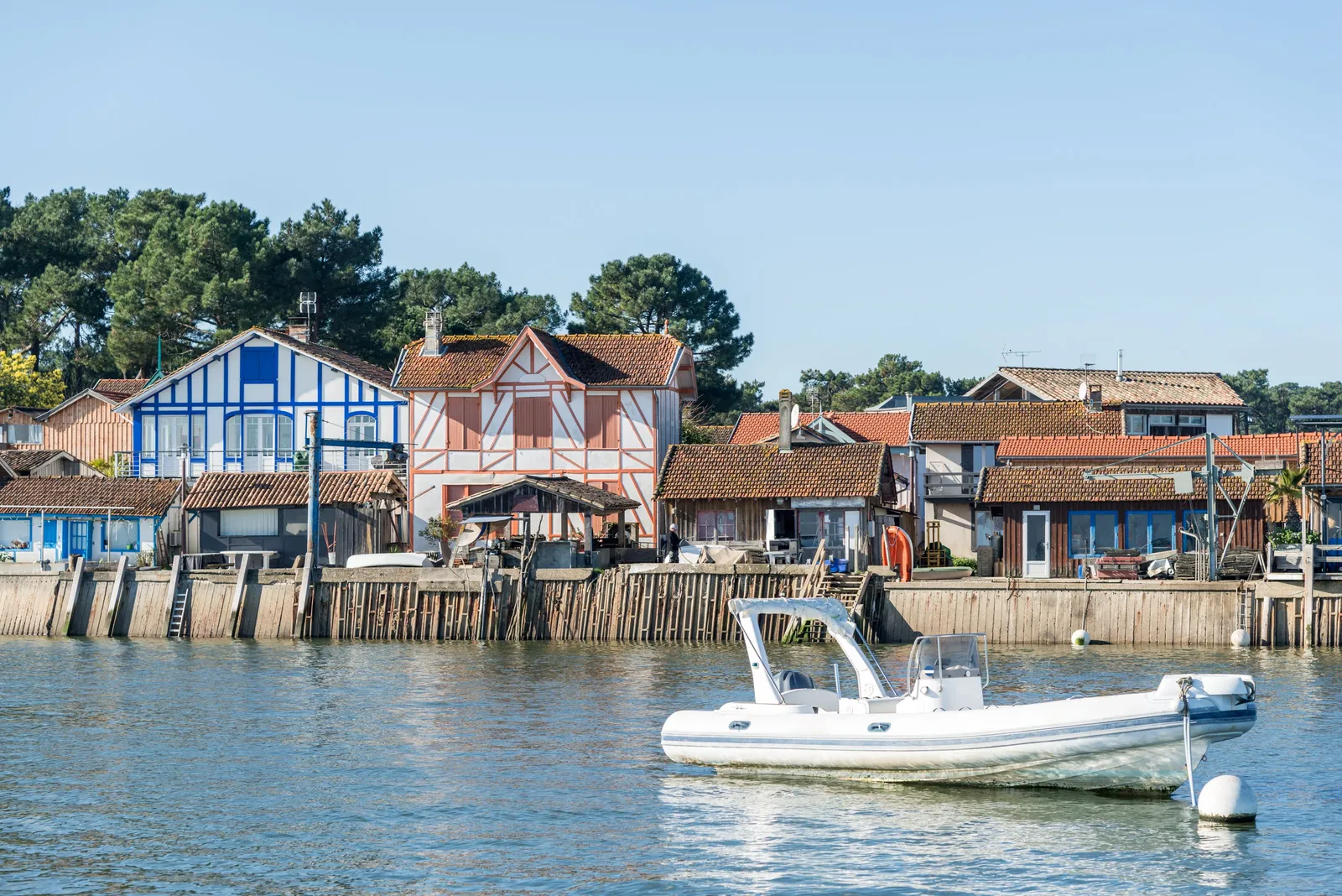 The oyster harbour of Piraillan on the Cap Ferret peninsula: colourful cabins beneath the pines and a boat at anchor