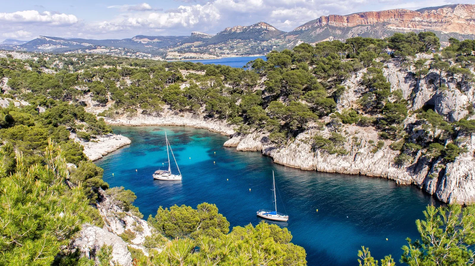 Uma calanque de Cassis e os seus veleiros, o cabo Canaille ao fundo