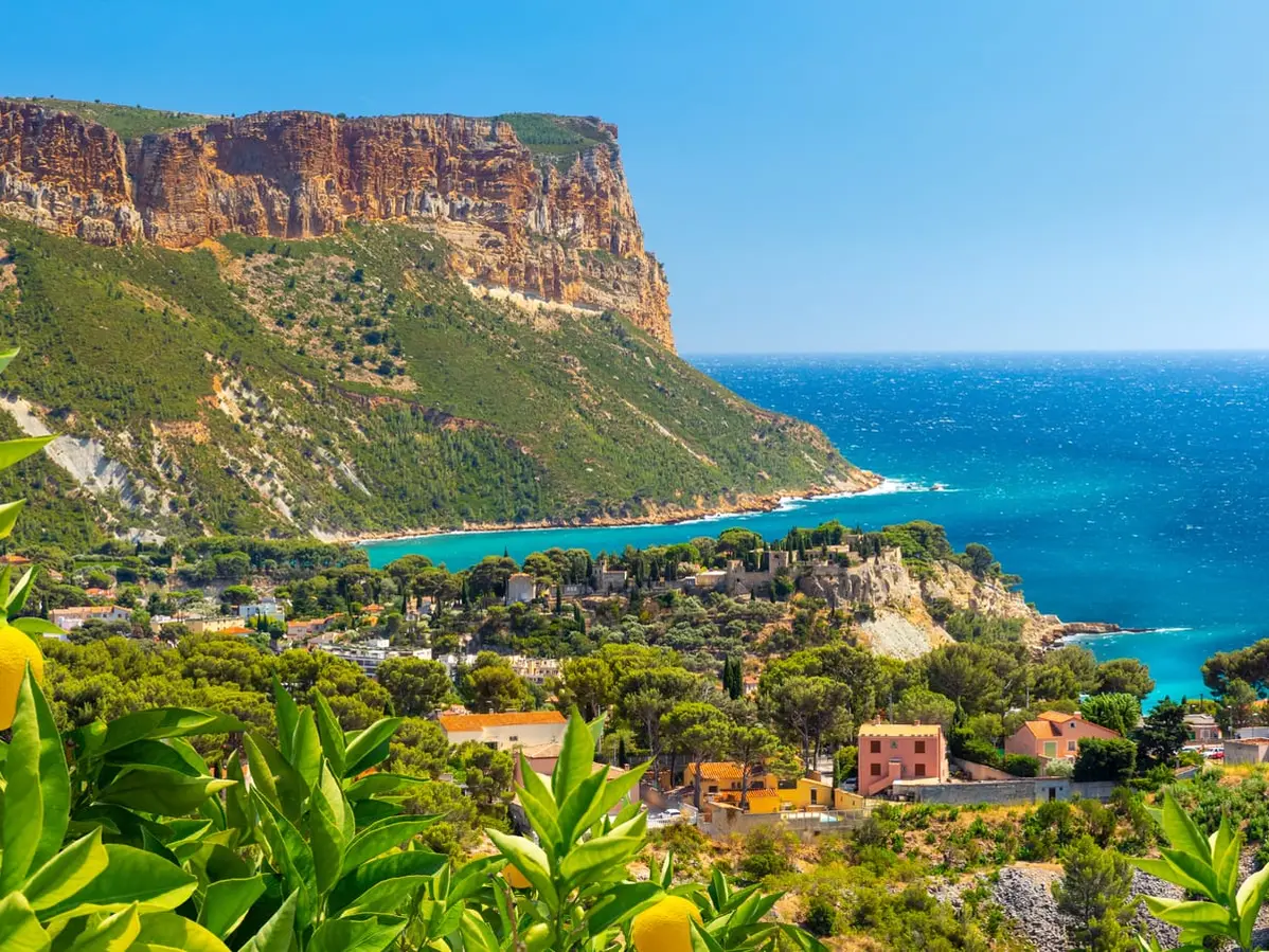 O cabo Canaille acima do mar e das casas de Cassis, um limoeiro em primeiro plano