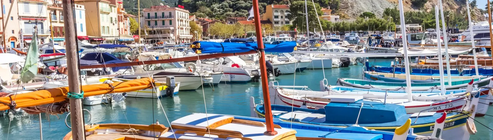 Traditional boats and yachts in Cassis harbour, with the castle on its hill