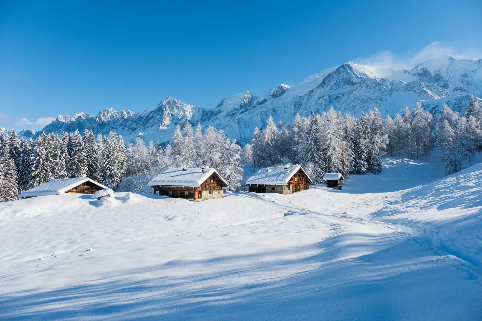 Des chalets dans la neige, au pied des sommets
