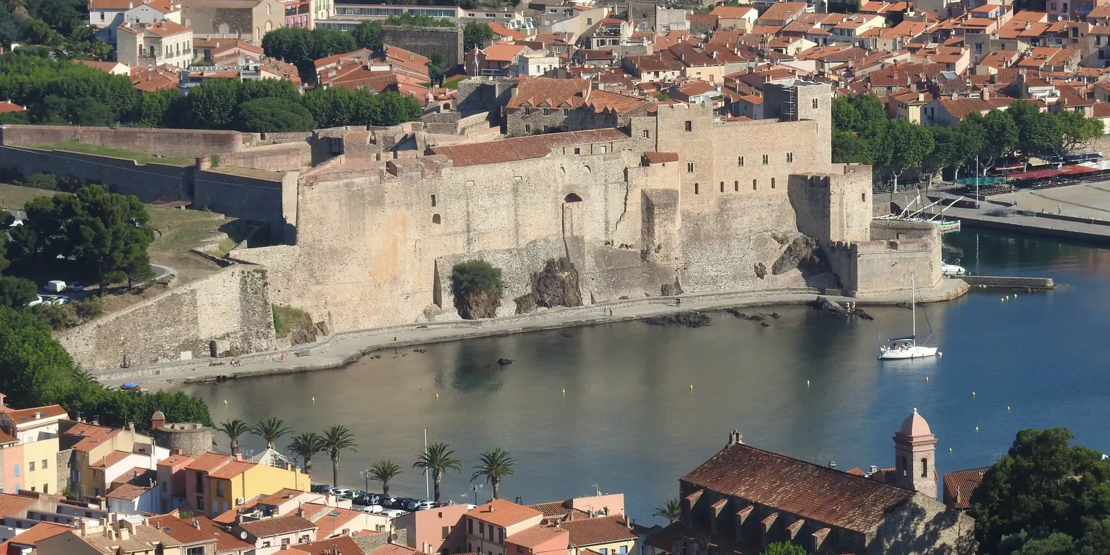 Collioure vue du ciel : le château royal au bord de l’anse, le centre ancien et ses toits, le port