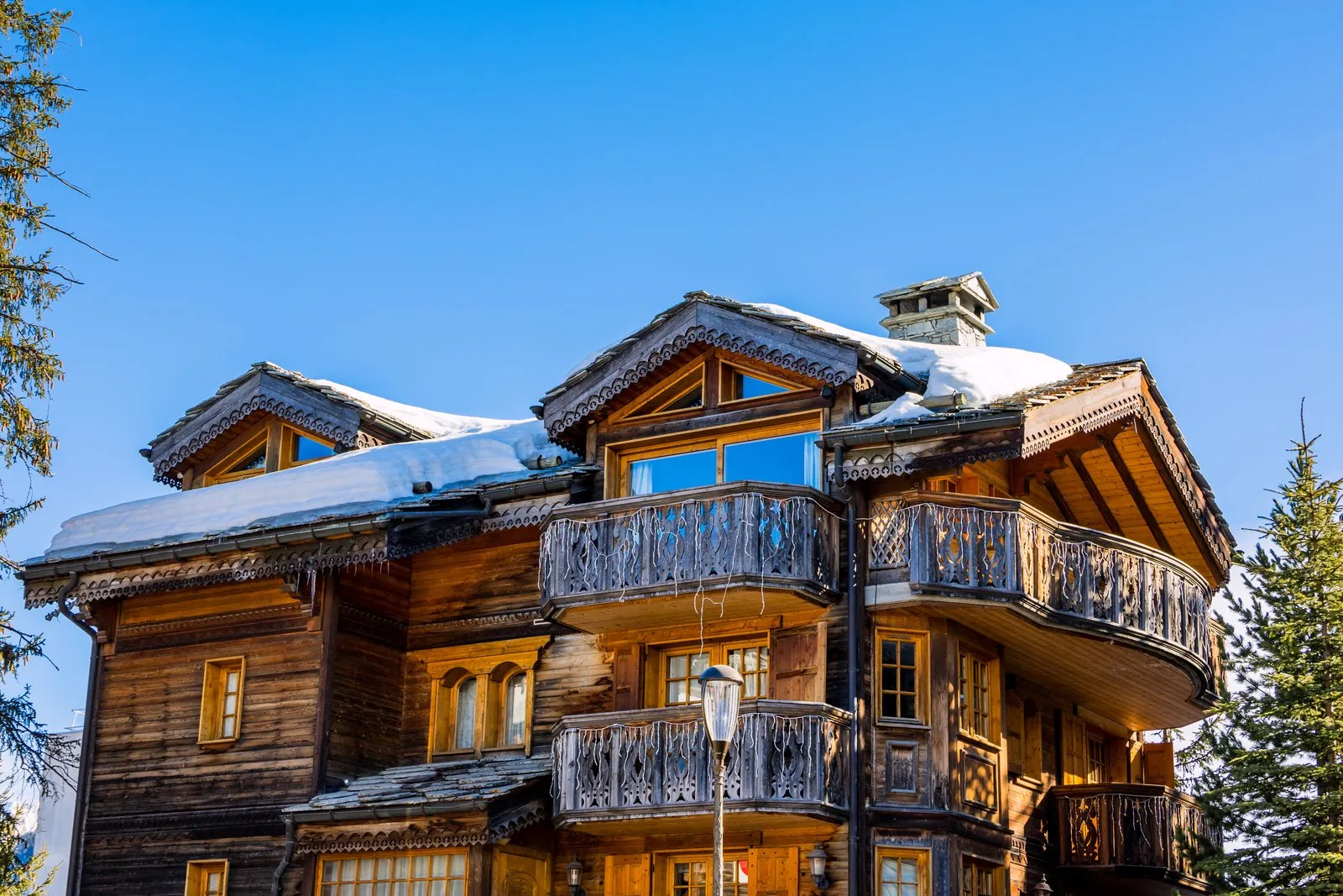 Un grand chalet de bois et ses balcons, sous la neige