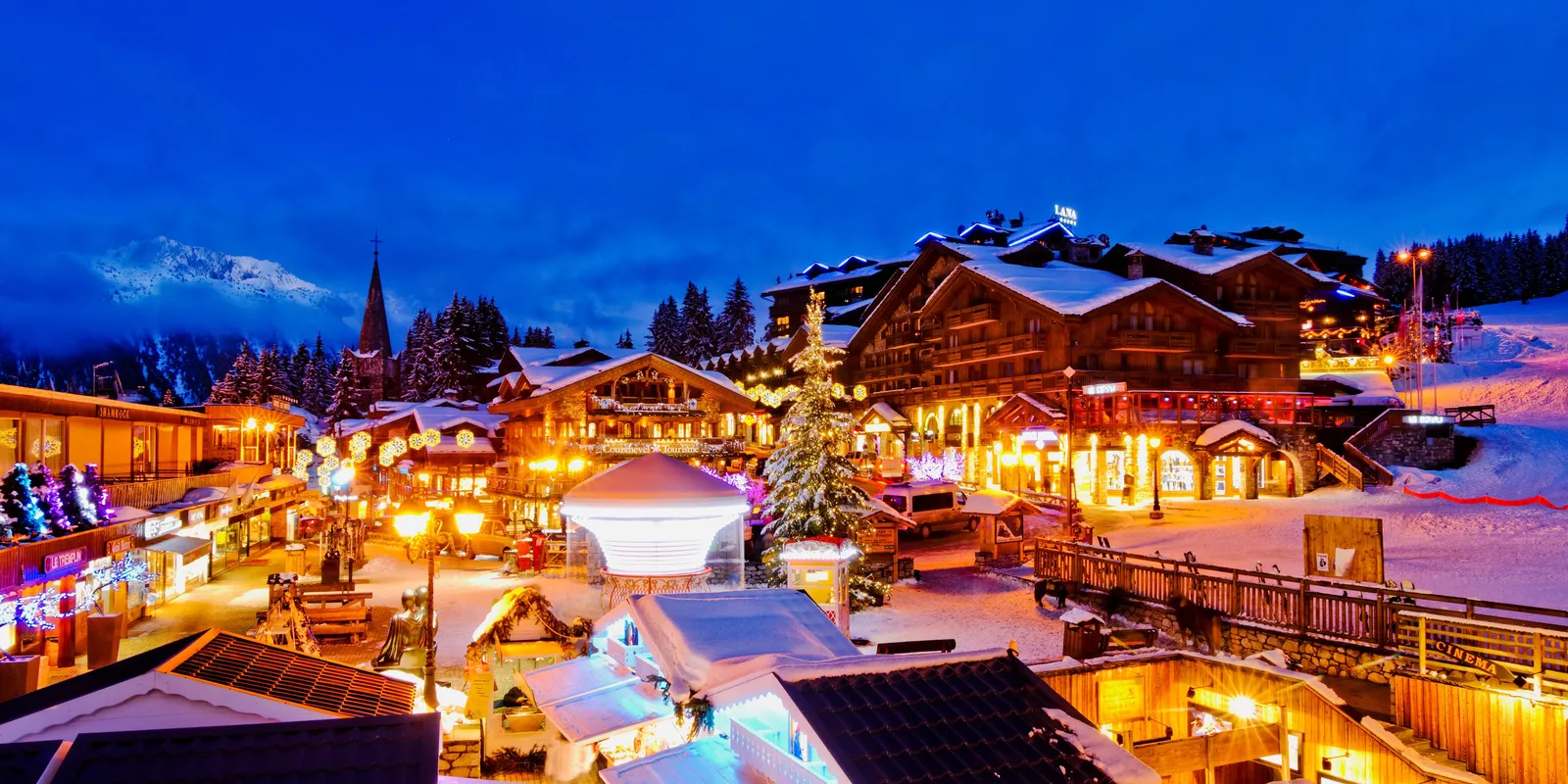 Le village illuminé à la nuit tombée, ses chalets sous la neige