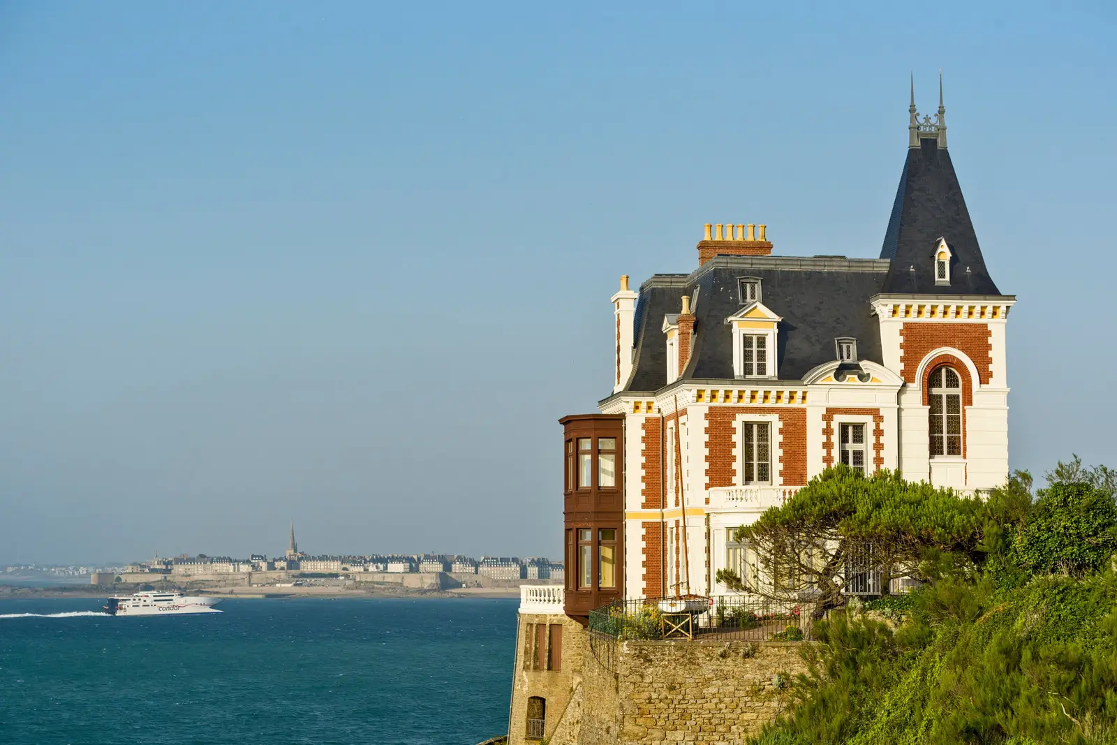 A villa Les Roches Brunes em Dinard, a sua torre de ardósia sobre o mar, e Saint-Malo na outra margem