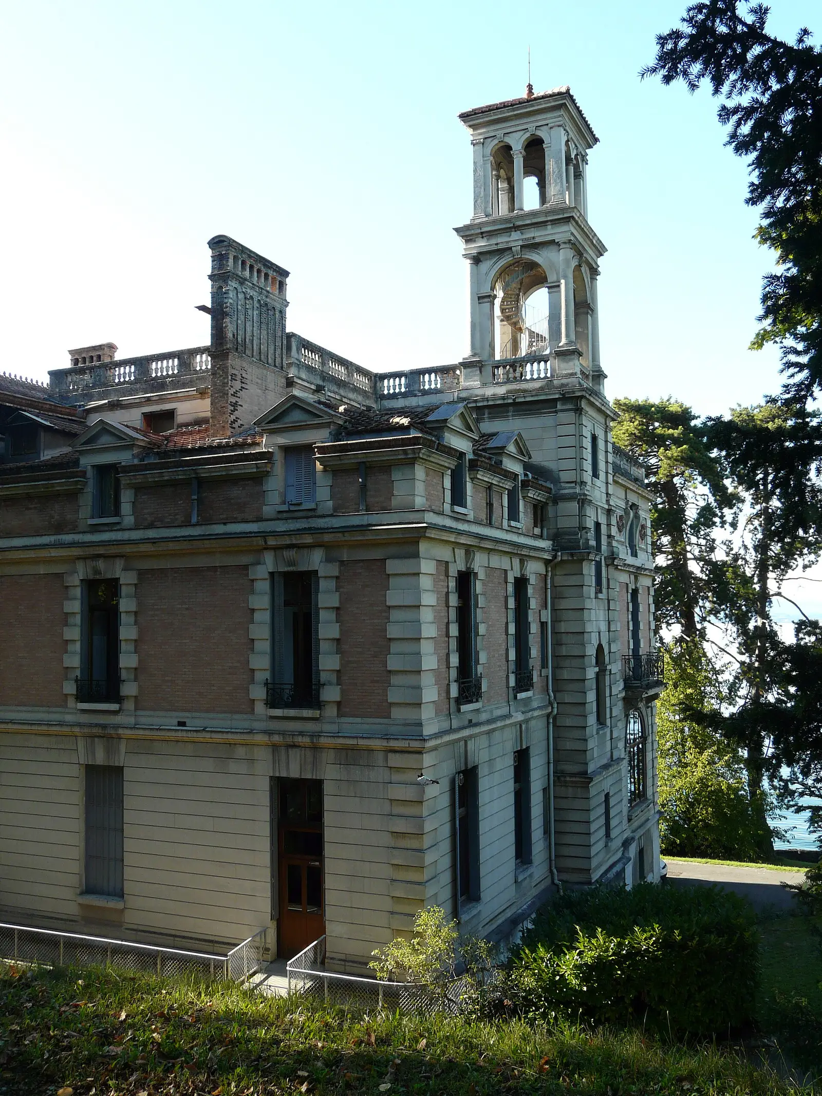 Grande moradia em Évian-les-Bains em pedra clara, torre com balaustrada e jardim de coníferas