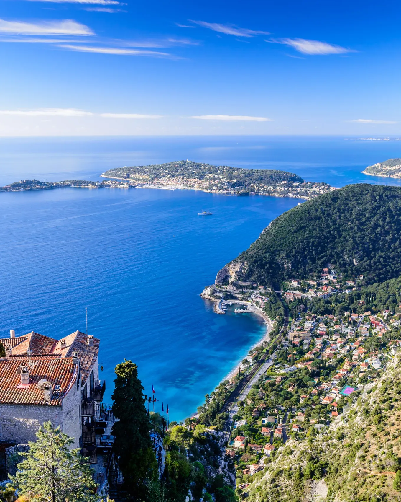 Èze village vu des hauteurs : ses toits de pierre au-dessus de la Méditerranée et la côte et ses caps à l’horizon