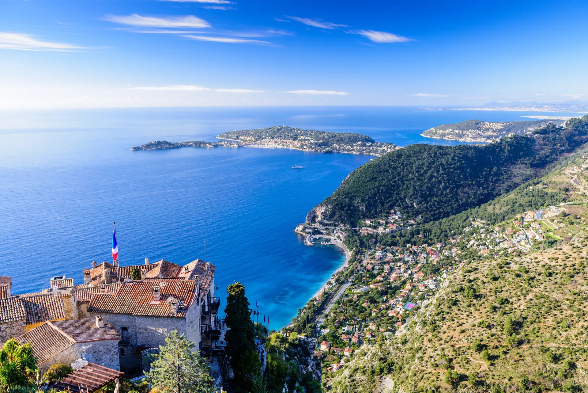 Èze village vu des hauteurs : ses toits de pierre au-dessus de la Méditerranée et la côte et ses caps à l’horizon