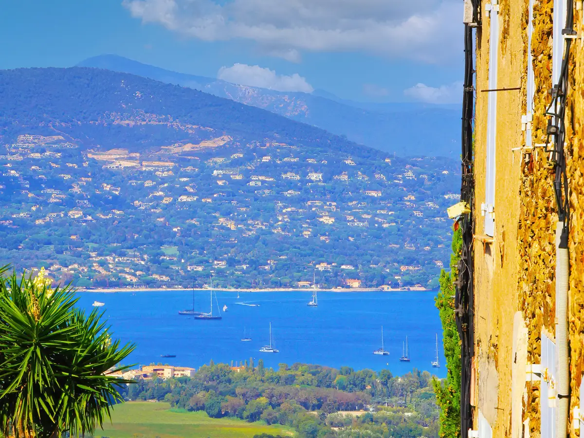 A lane in the hilltop village of Gassin and, below, the Gulf of Saint-Tropez with its yachts and its hills dotted with villas