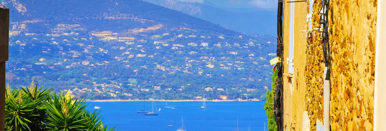 A lane in the hilltop village of Gassin and, below, the Gulf of Saint-Tropez with its yachts and its hills dotted with villas