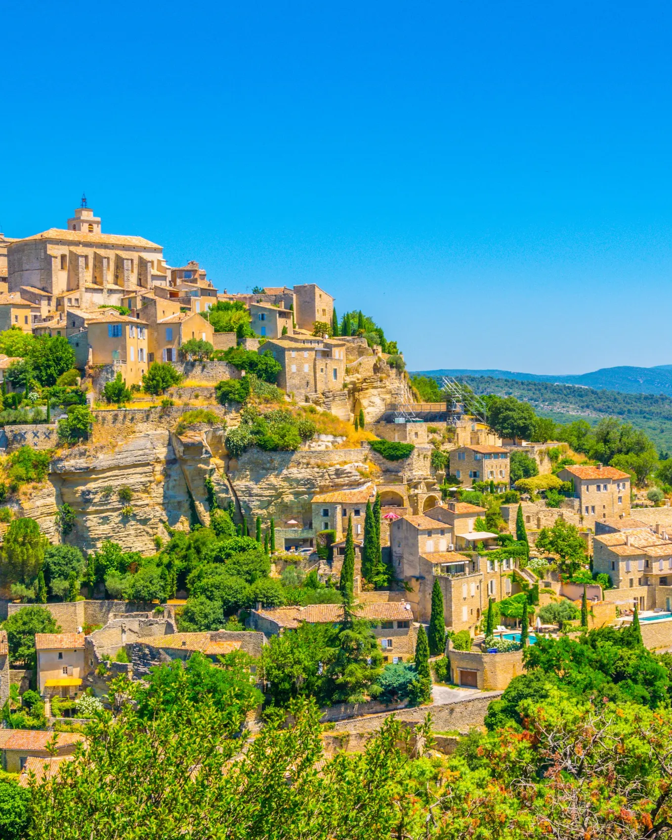 Gordes accroché à son rocher, ses maisons de pierre étagées sous le château et l’église, face au Luberon