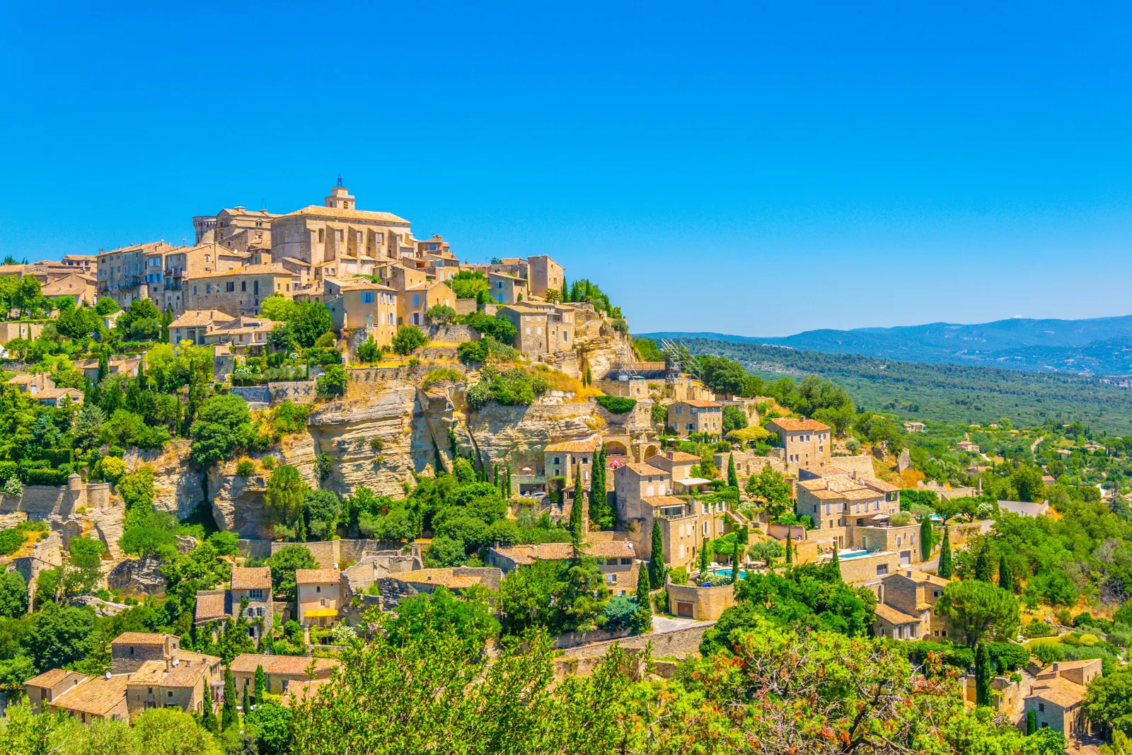 Gordes clinging to its rock, its stone houses stepped below the château and the church, facing the Luberon
