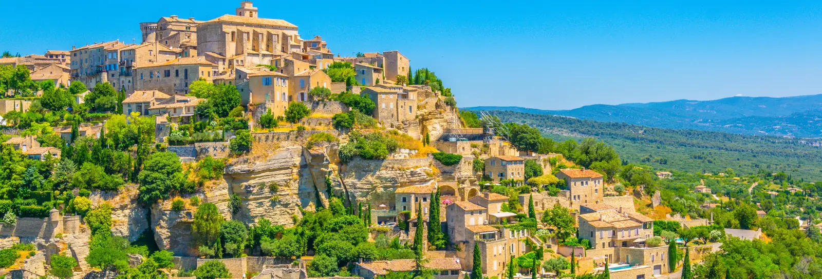 Gordes clinging to its rock, its stone houses stepped below the château and the church, facing the Luberon