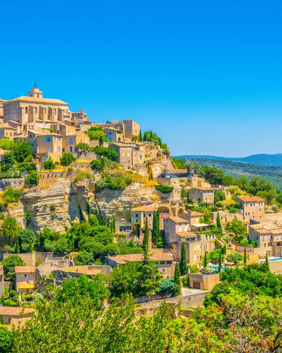 Gordes clinging to its rock, its stone houses stepped below the château and the church, facing the Luberon