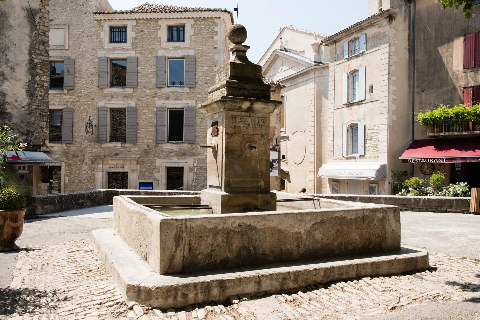 A fonte de pedra de uma praça de Gordes, a aldeia empoleirada do Luberon, e as suas fachadas de portadas cinzentas