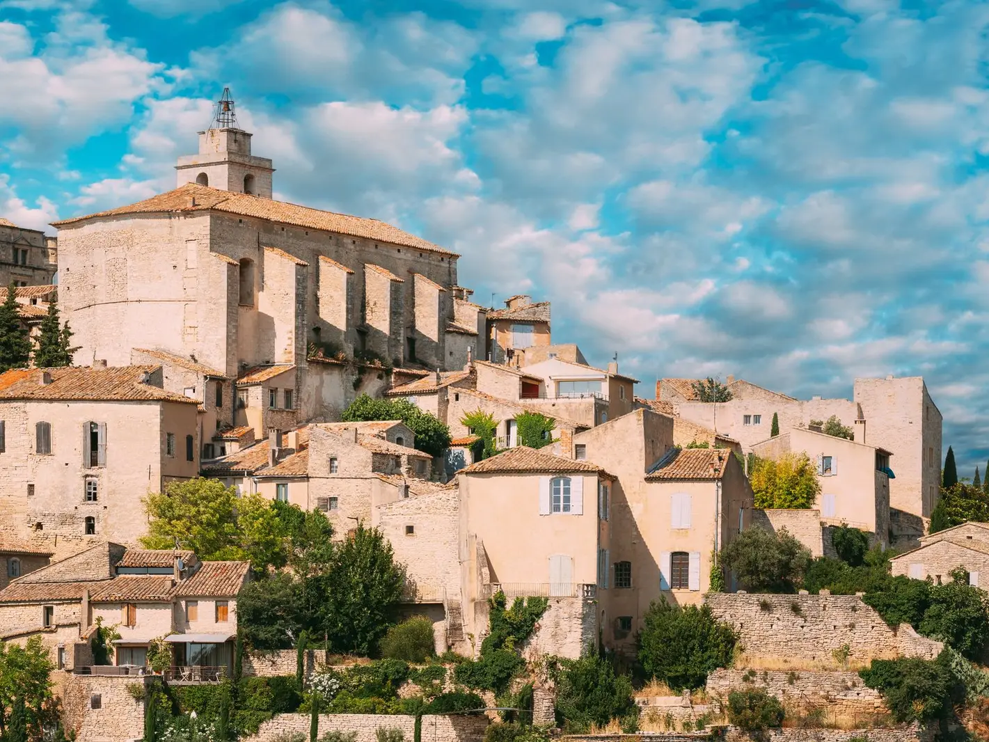 As casas de pedra de Gordes apertadas em torno da igreja de Saint-Firmin e do seu campanário, sob um céu de nuvens