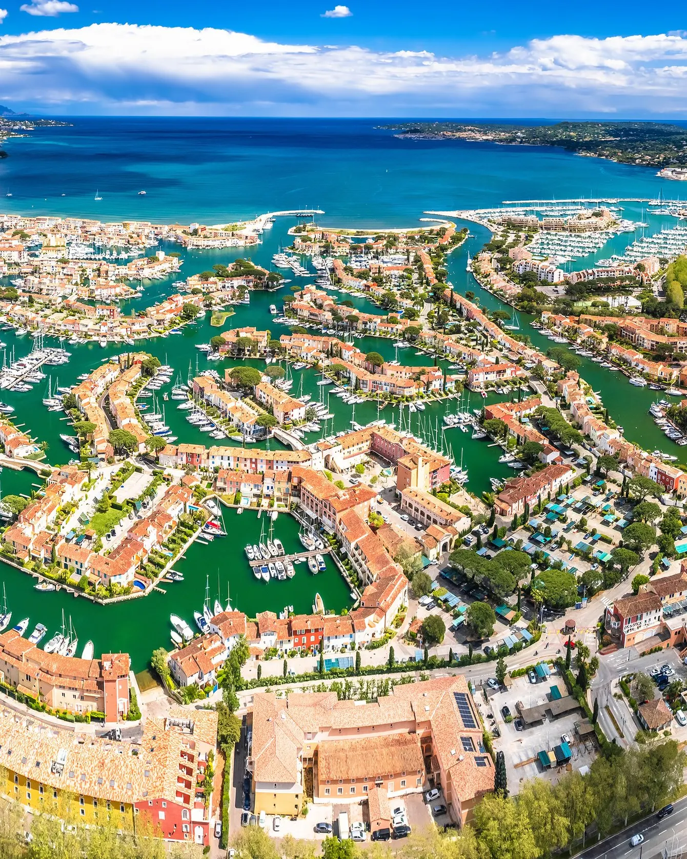 Port Grimaud from the air: the lakeside village, its canals and houses, the Gulf of Saint-Tropez beyond