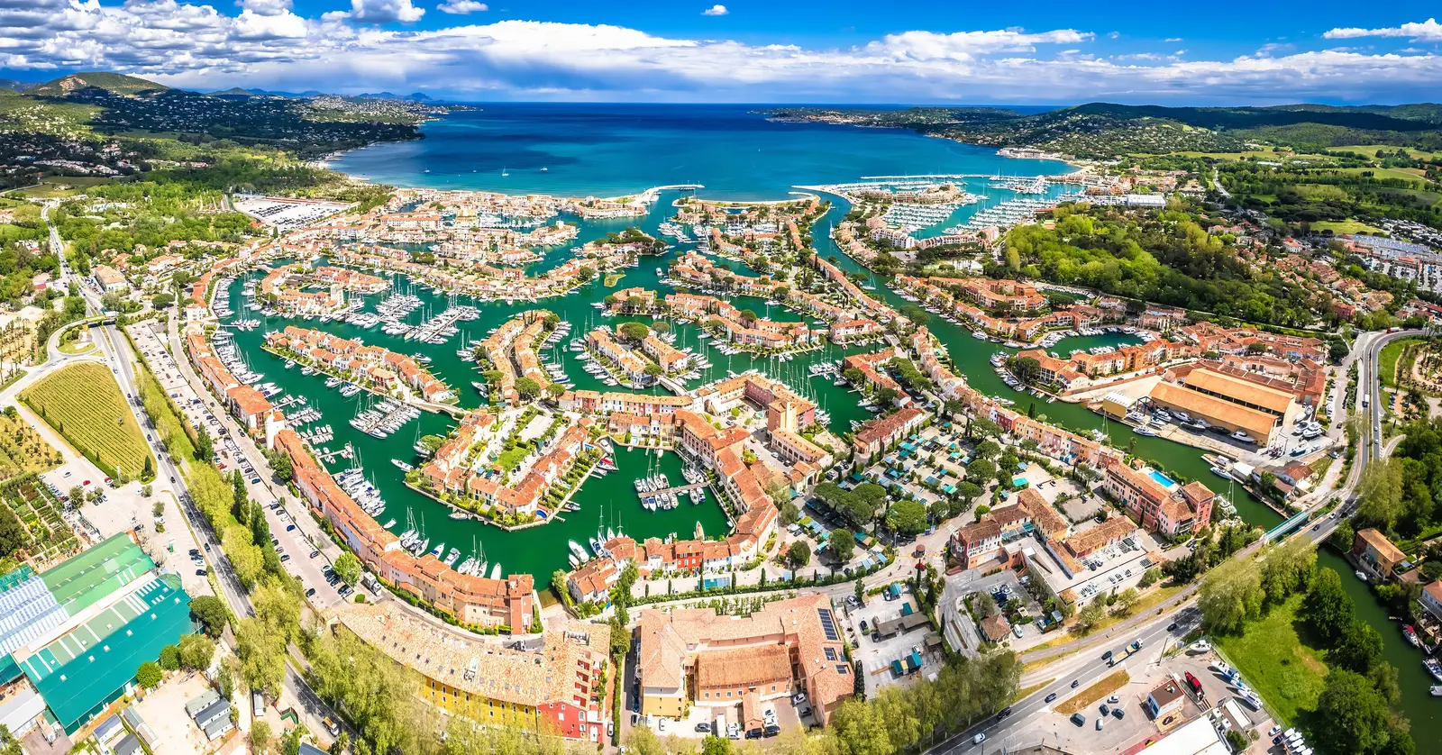 Port Grimaud from the air: the lakeside village, its canals and houses, the Gulf of Saint-Tropez beyond