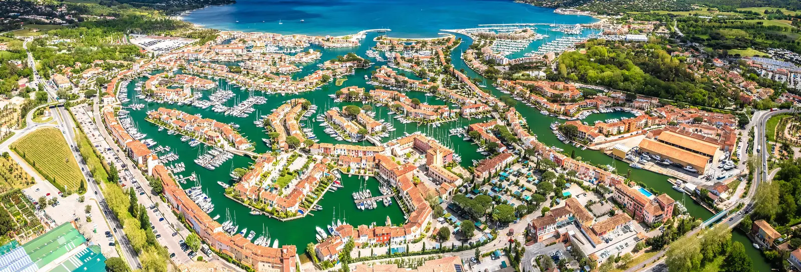 Port Grimaud from the air: the lakeside village, its canals and houses, the Gulf of Saint-Tropez beyond