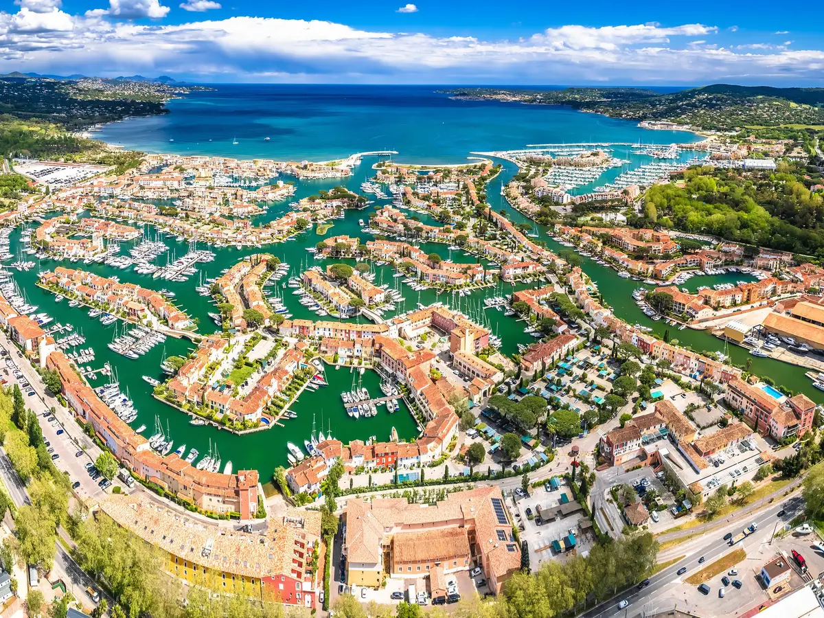 Port Grimaud from the air: the lakeside village, its canals and houses, the Gulf of Saint-Tropez beyond