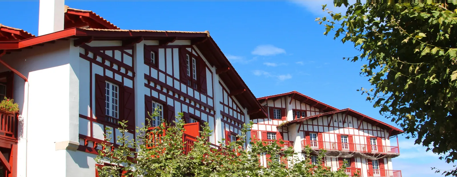 Les villas basques de Guéthary, leurs colombages rouges et leurs balcons de bois sous le ciel bleu