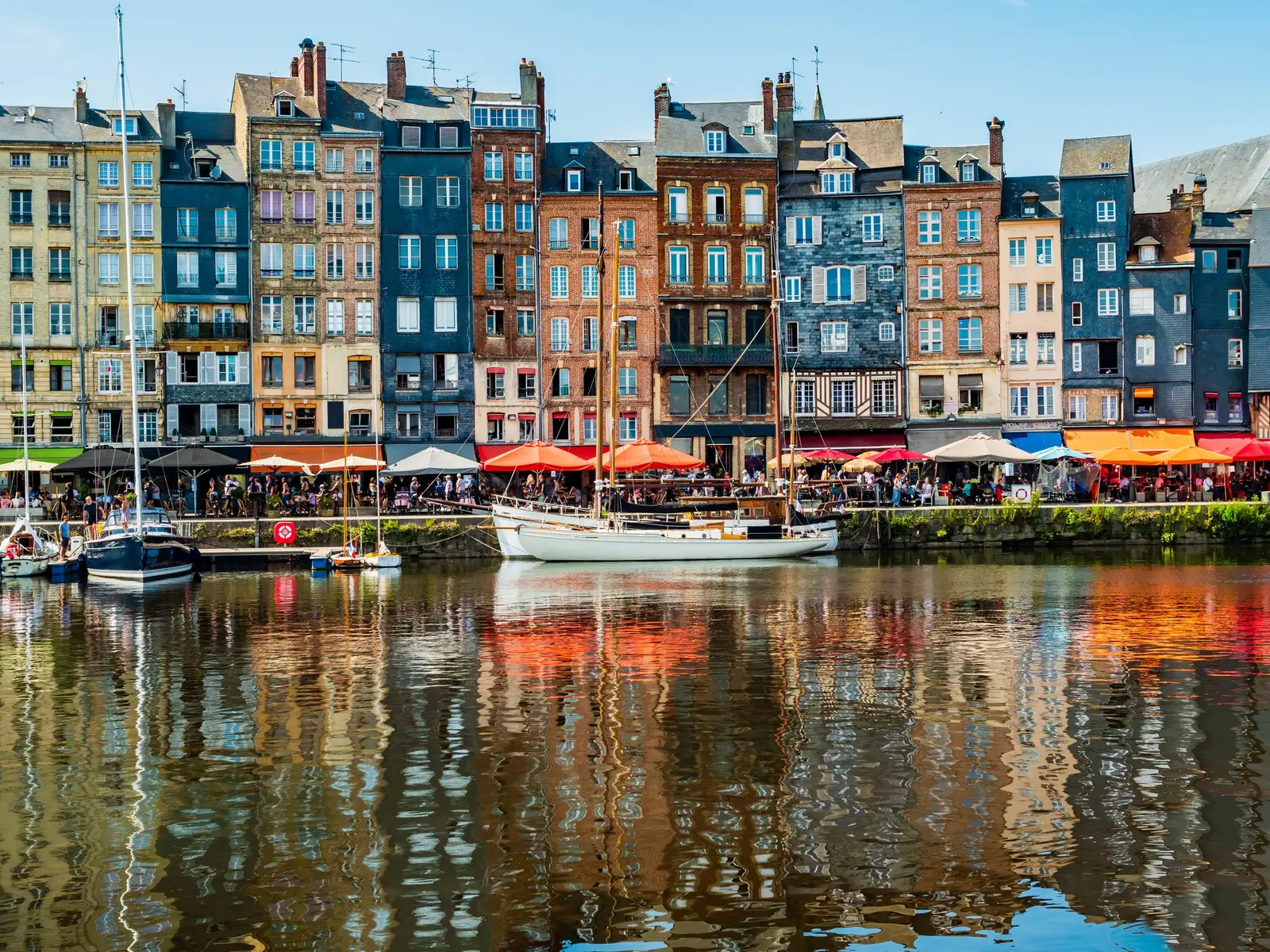 Les hautes façades étroites d’ardoise et de bois du Vieux Bassin de Honfleur, leurs terrasses et leur reflet dans l’eau
