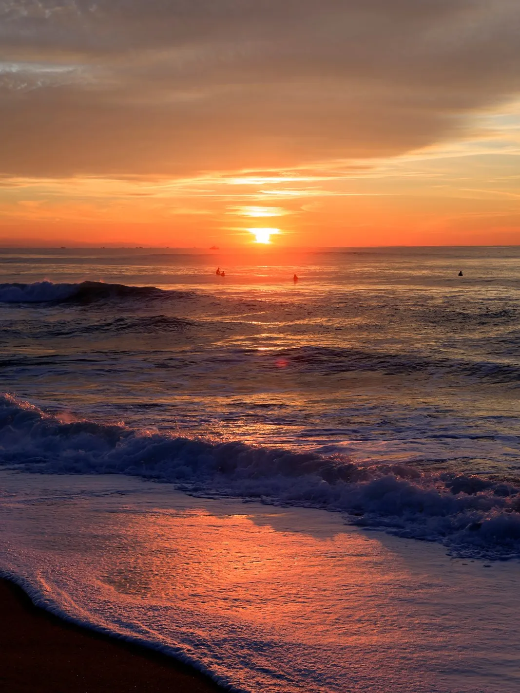 Le soleil se couche sur l’océan à Hossegor, les vagues reflètent le ciel orangé