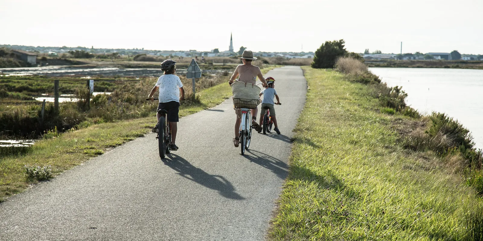 Uma família de bicicleta numa ciclovia da ilha de Ré, entre os pântanos salgados