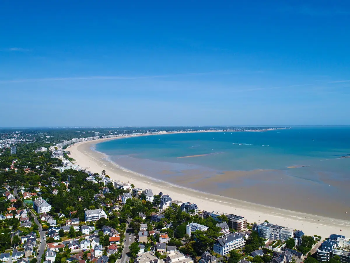 A baía de La Baule vista do céu: a praia em arco, as moradias entre os pinheiros e o mar na maré baixa