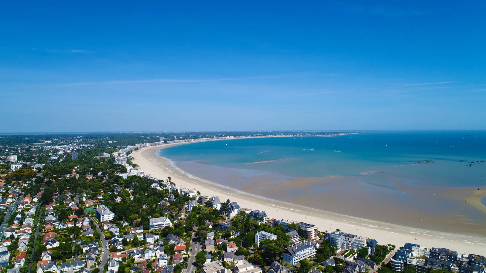 The bay of La Baule from the sky: the curving beach, the villas among the pines and the sea at low tide